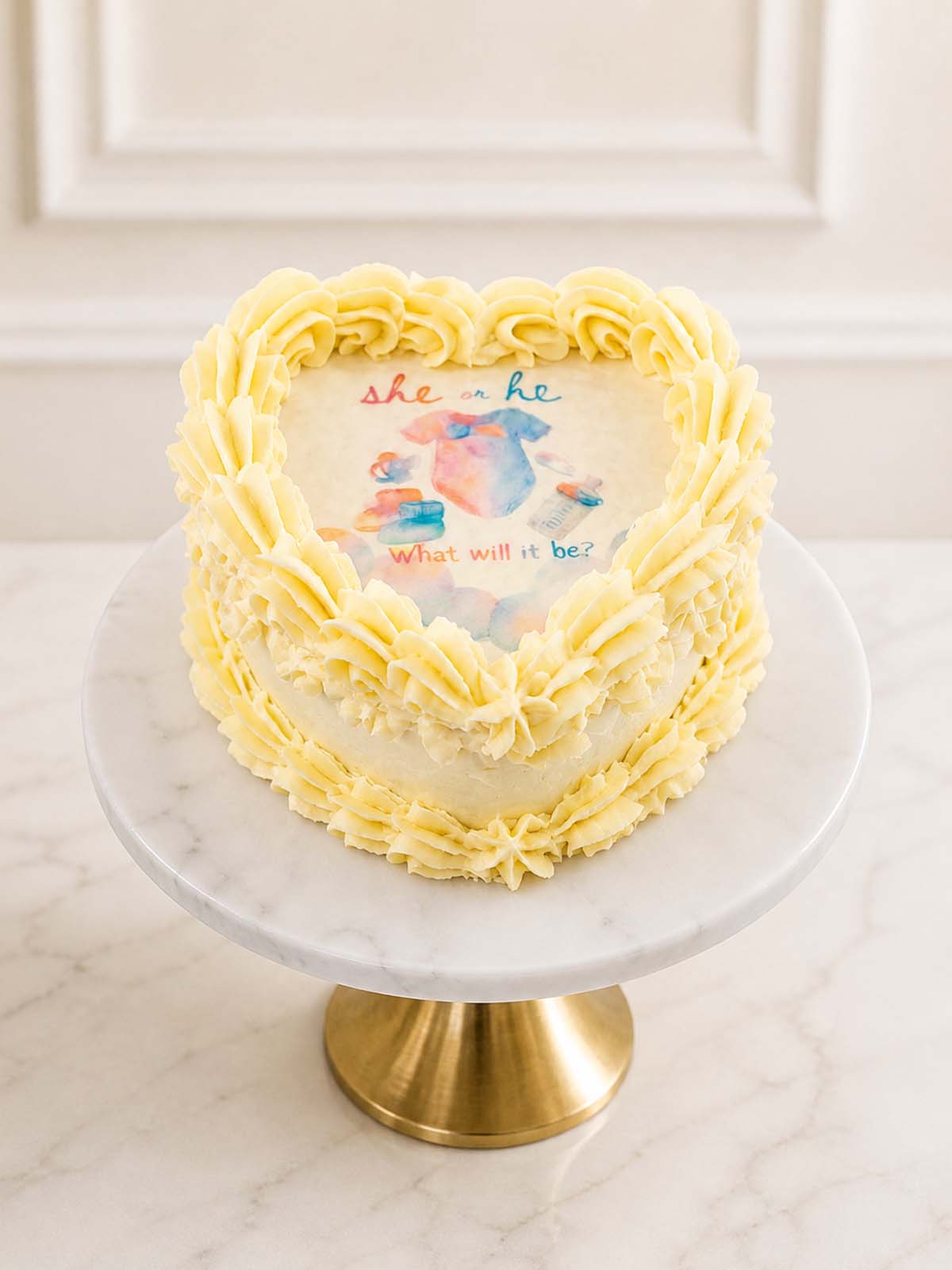 Heart-shaped burn-away gender reveal cake with a fire-reveal top layer and pink or blue vanilla sponge. Finished with vanilla Swiss meringue buttercream and delivered in London.