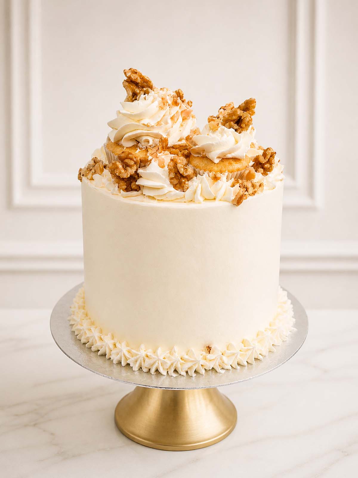 Luxury carrot cake with three spiced sponge layers, vanilla Swiss meringue buttercream, crushed walnuts, and a crown of mini cupcakes. Delivered in London and Surrey.