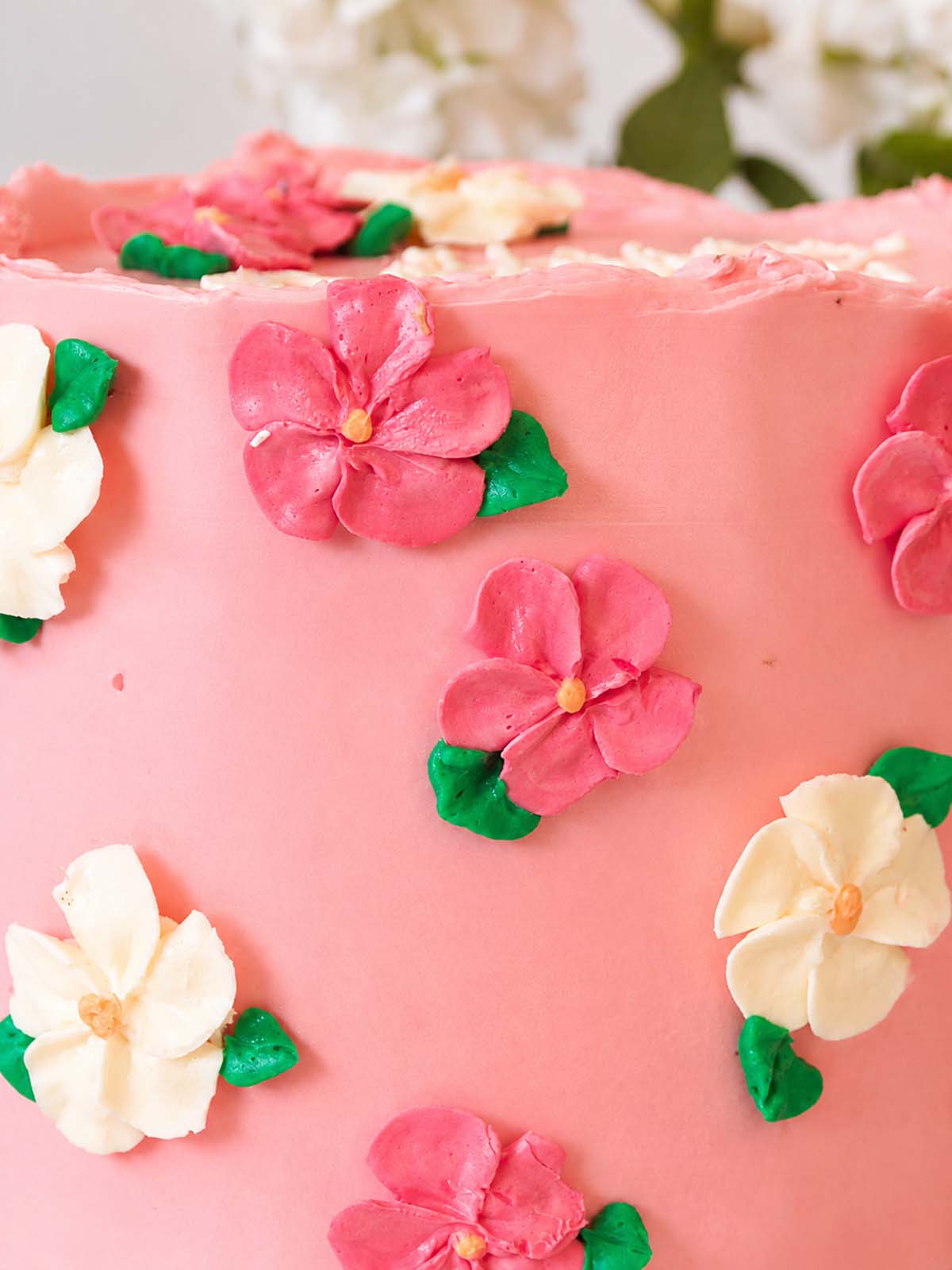 Close-up of a pink floral birthday cake with floral decorations handmade and delivered in Surrey (UK). 