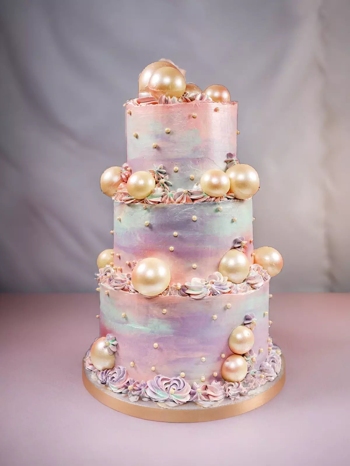 Three-tier cake with pastel watercolor frosting, edible pearls, and small white sprinkles