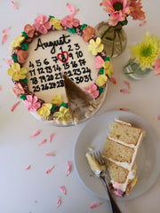 August calendar cake with a slice removed, next to a plate with a slice of cake and a fork