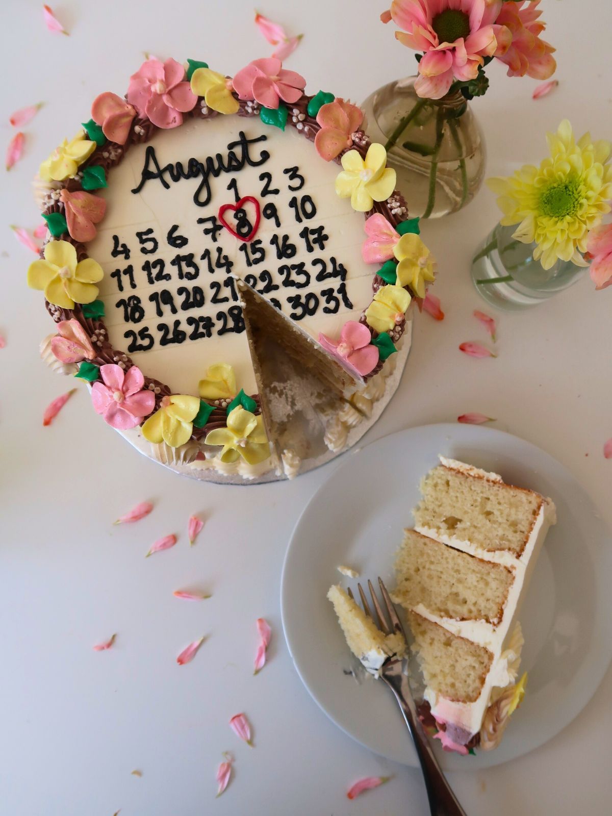 August calendar cake with a slice removed, next to a plate with a slice of cake and a fork