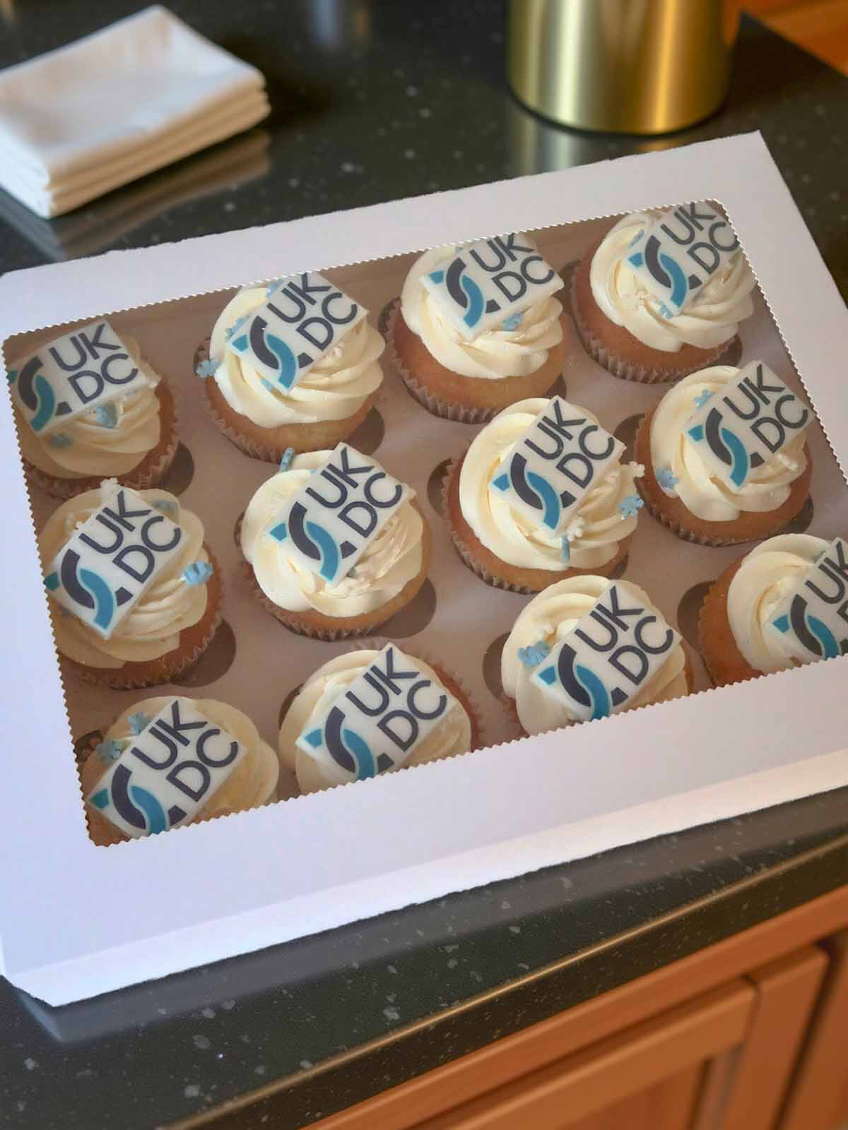 Box of branded cupcakes with 'UK DC' branding.