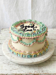 Good Luck cake with pastel green, pink, yellow, and blue frosting