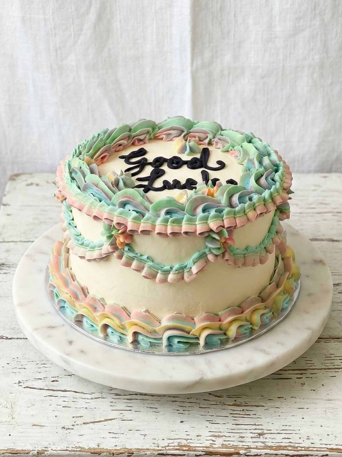 Good Luck cake with pastel green, pink, yellow, and blue frosting