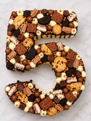 Number 5-shaped cake decorated with various cookies and candies on a marble surface delivered in London.