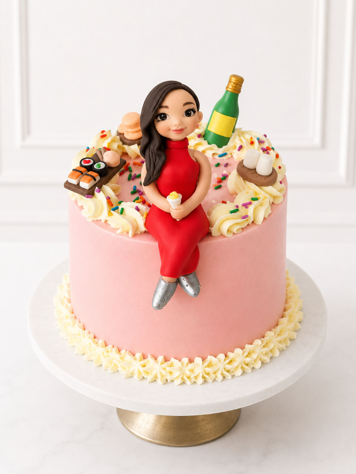Pink cake with a figurine of a woman in a red dress, surrounded by food items and a bottle on a white background.
