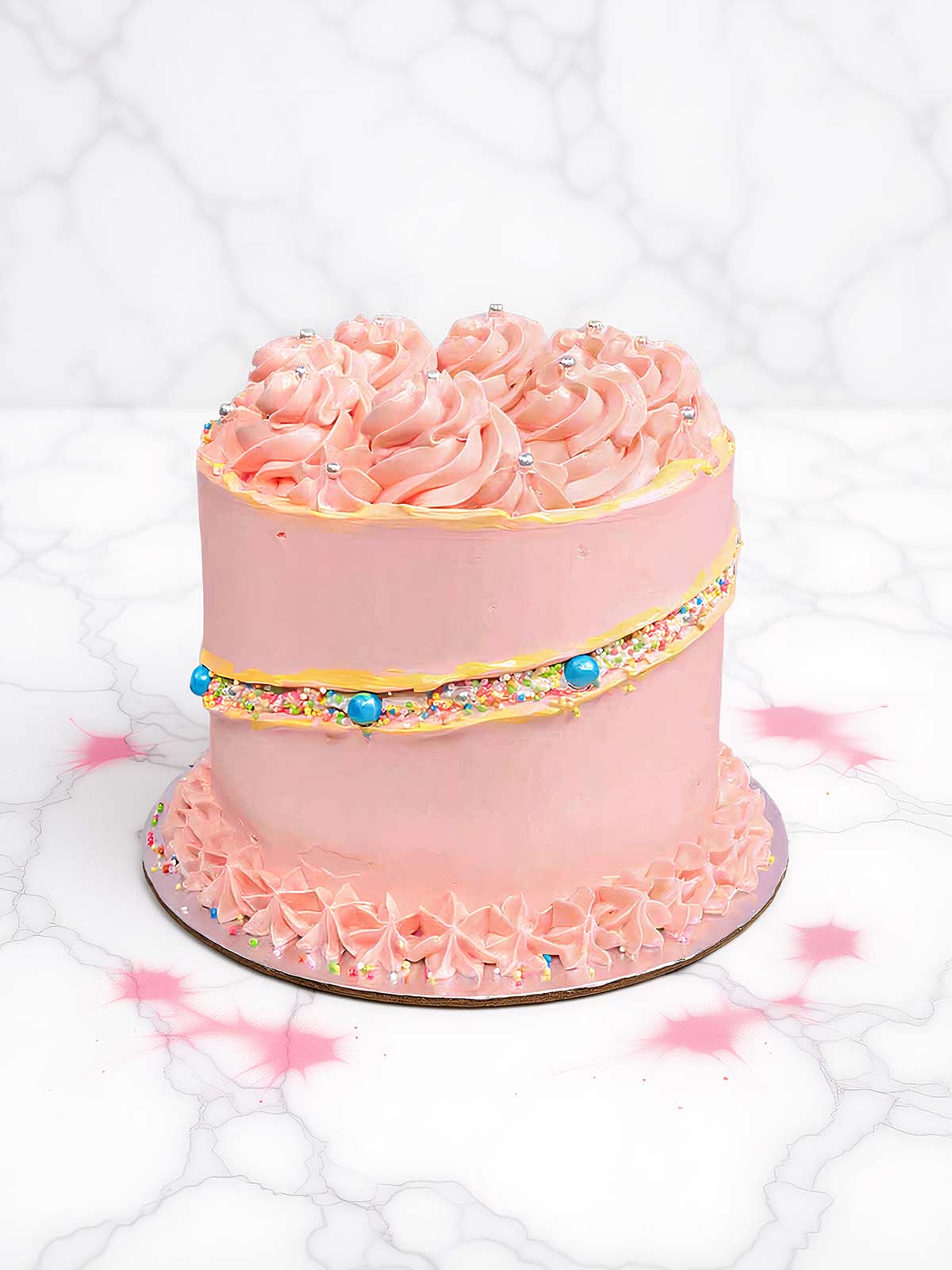 Pink cake with sprinkles and blue candies on a white marble background