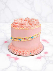 Pink cake with sprinkles and blue candies on a white marble background