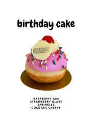 Birthday cake doughnut with pink glaze, sprinkles, cherry, and Hero Doughnuts logo