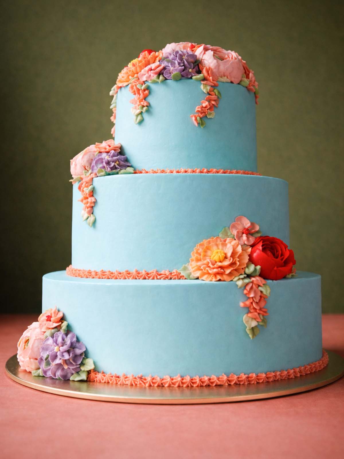 Elegant blue 3-tier wedding cake with hand-piped floral meadow decorations, available for delivery in Surrey and London.