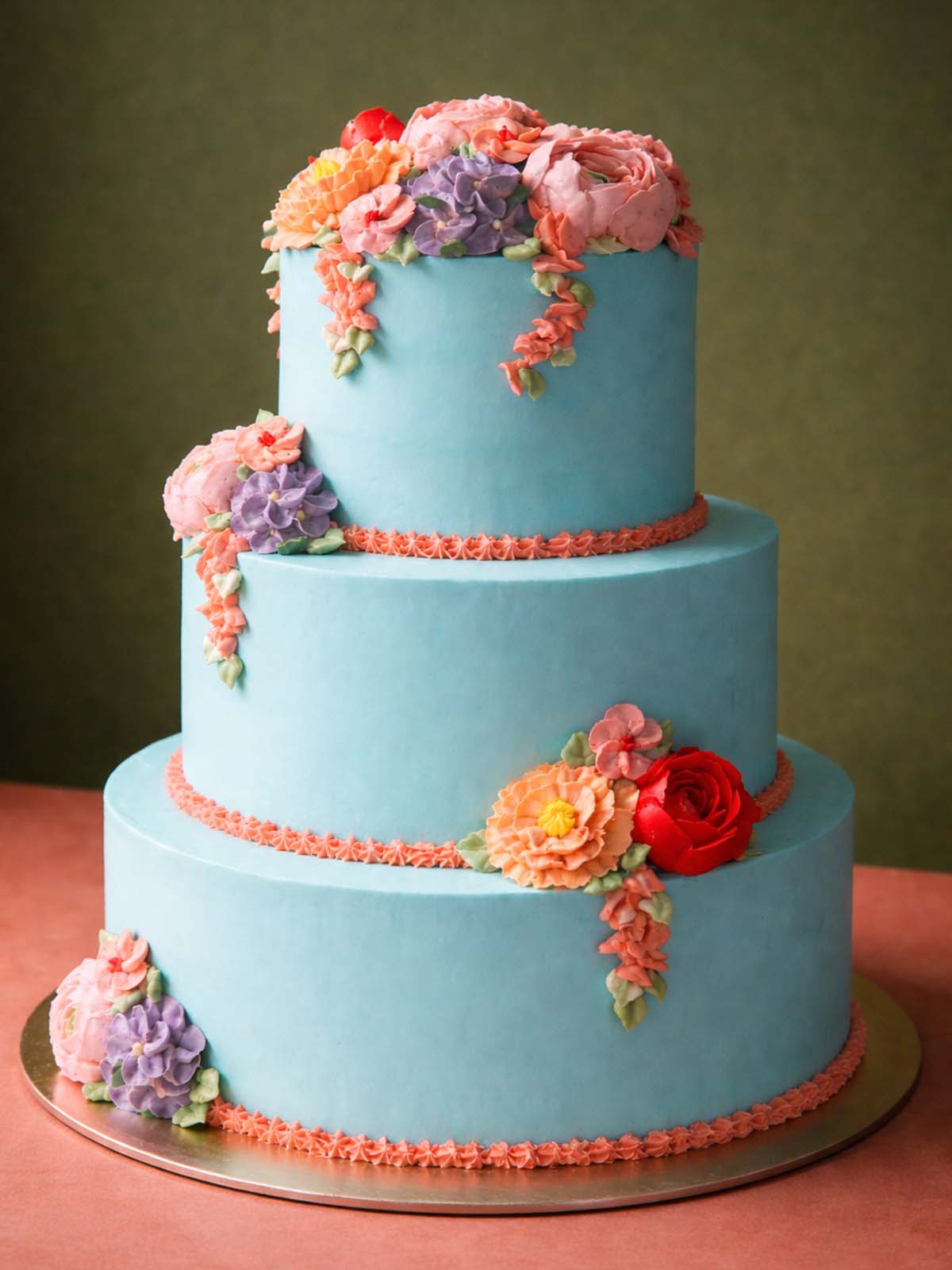 A professional three-tier Floral Buttercream Wedding Cake with intricate hand-piped flower cascades, hand-delivered across London.