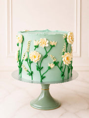 Elegant celebration cake featuring an intricate cascade of hand-piped Swiss meringue buttercream ivory flowers, buds, and foliage