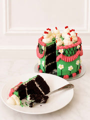 Slice of Kitsch Chicken Cake showing rich Belgian chocolate sponge, green buttercream, pink piping and creamy vanilla filling.