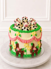 Kitsch Cow Cake with Belgian chocolate sponge, vanilla Swiss meringue buttercream, hand-piped ruffles, blossoms, fencing and buttercream cows.