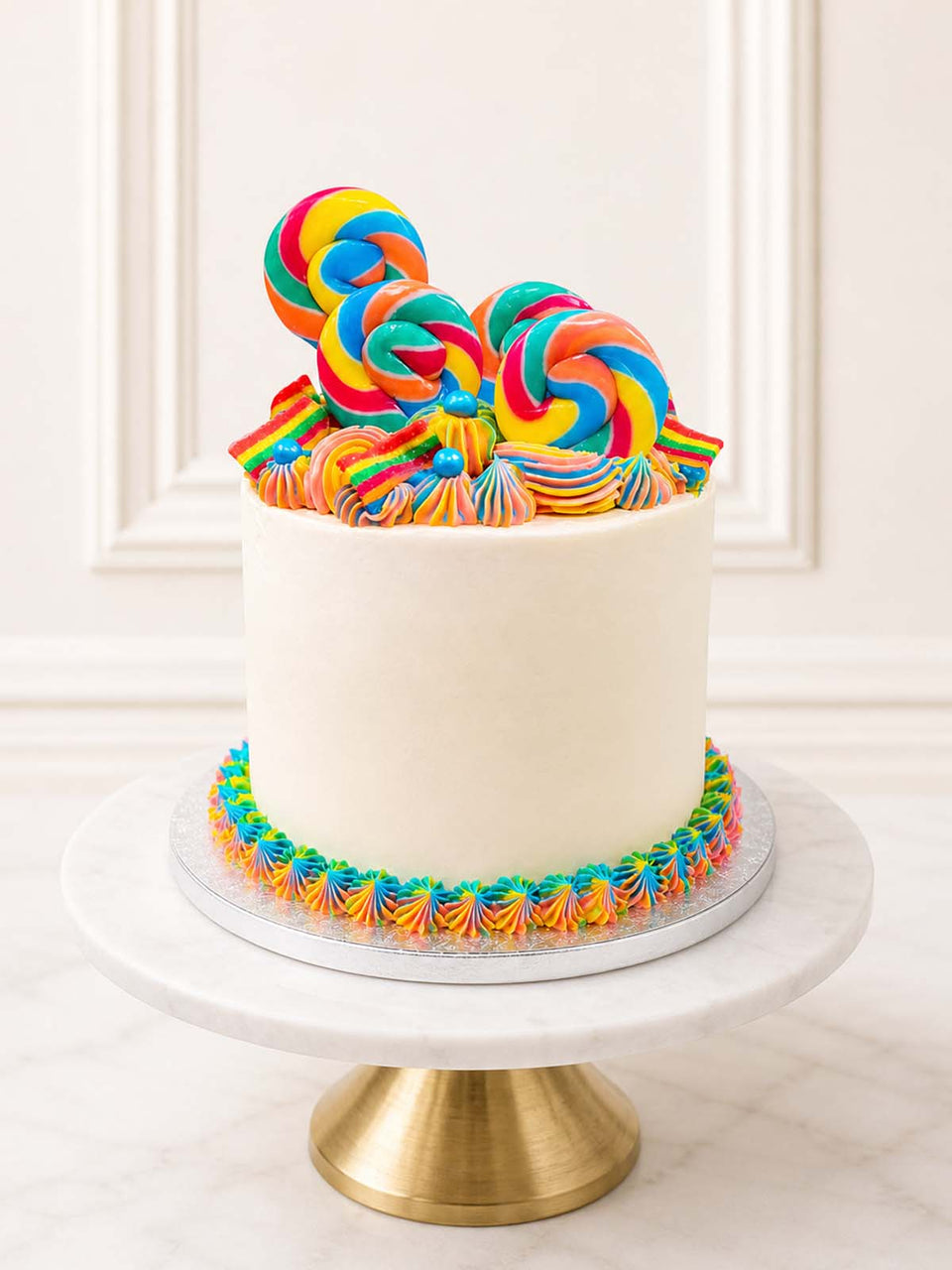 Luxury five-layer rainbow cake with lollipops and sprinkles, London and Surrey.
