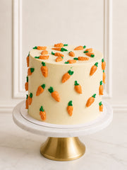 A luxury classic carrot celebration cake featuring three layers of moist spiced sponge, silky vanilla Swiss meringue buttercream, and charming hand-piped buttercream carrots. Handcrafted by a Michelin-trained chef and delivered across London and Surrey.