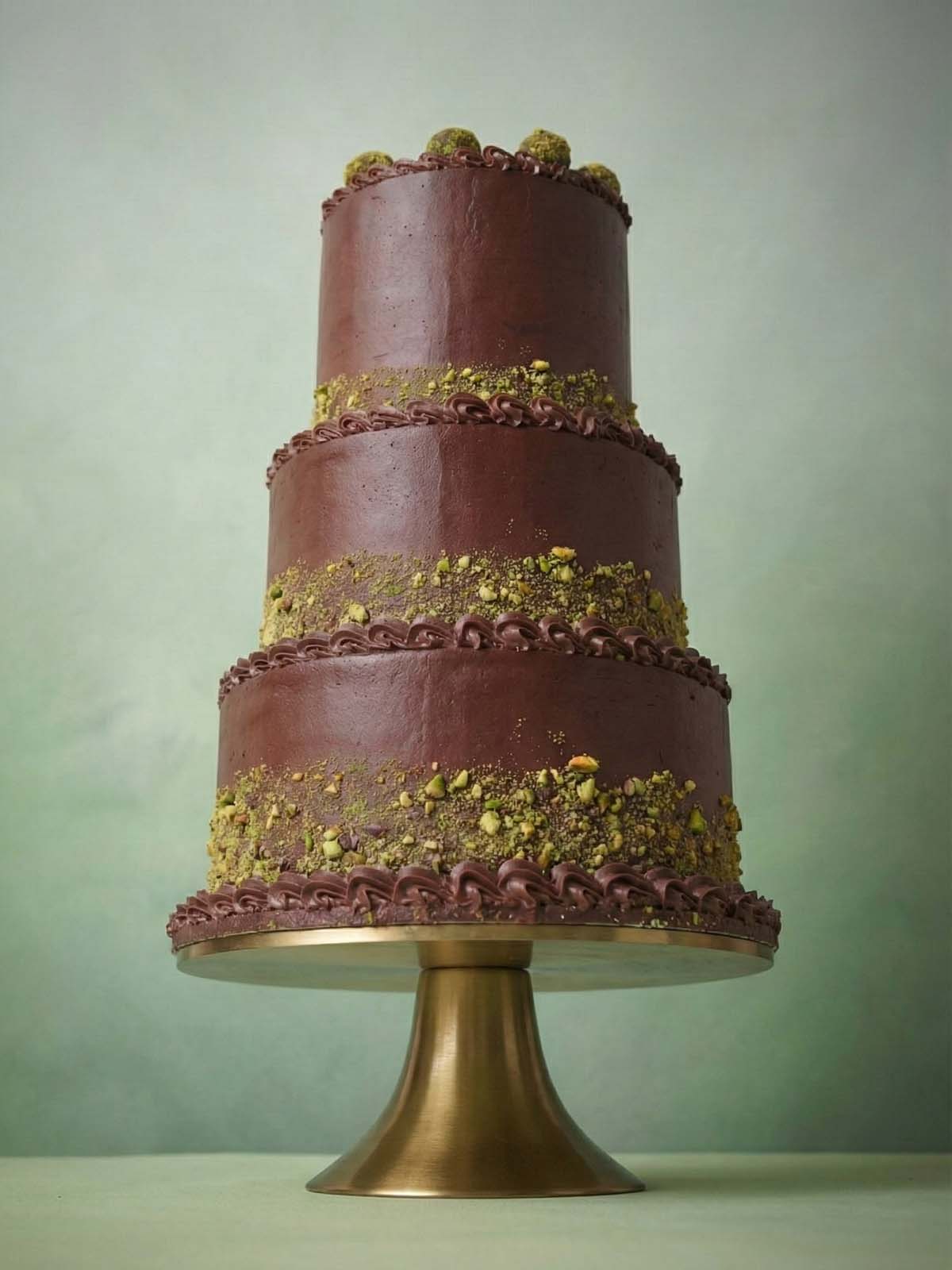 Luxury wedding cake with three tiers of rich chocolate ganache and vibrant green crushed pistachios, available for venues across London and Surrey.