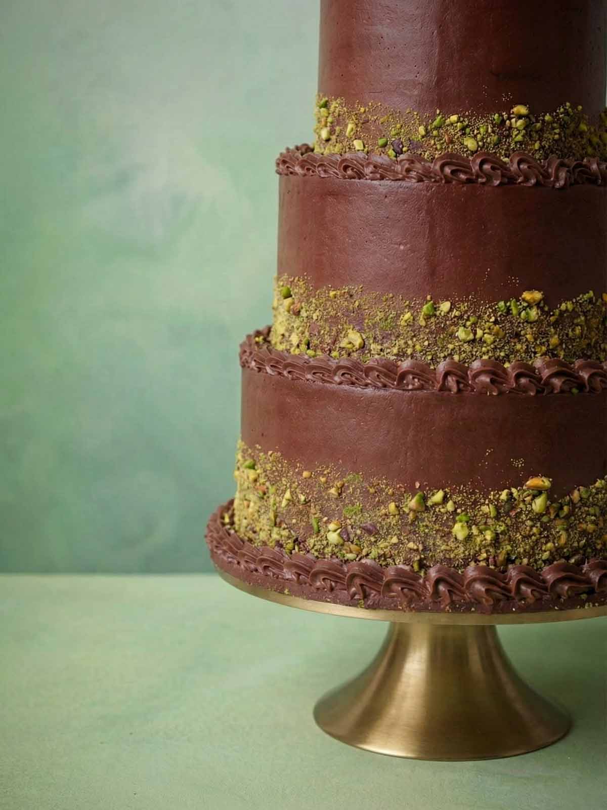 Modern chocolate wedding cake designed with clean tiers and pistachio accents, created by a leading cake designer for contemporary London weddings.