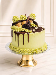 A playful yet sophisticated celebration cake featuring authentic Japanese matcha green tea sponge and matcha Swiss meringue buttercream mixed with crushed Oreos. Crowned with a Belgian chocolate drip, whole Oreo cookies, chocolate biscuit sticks, and whimsical mini matcha soft-serve cones. Delivered in London.