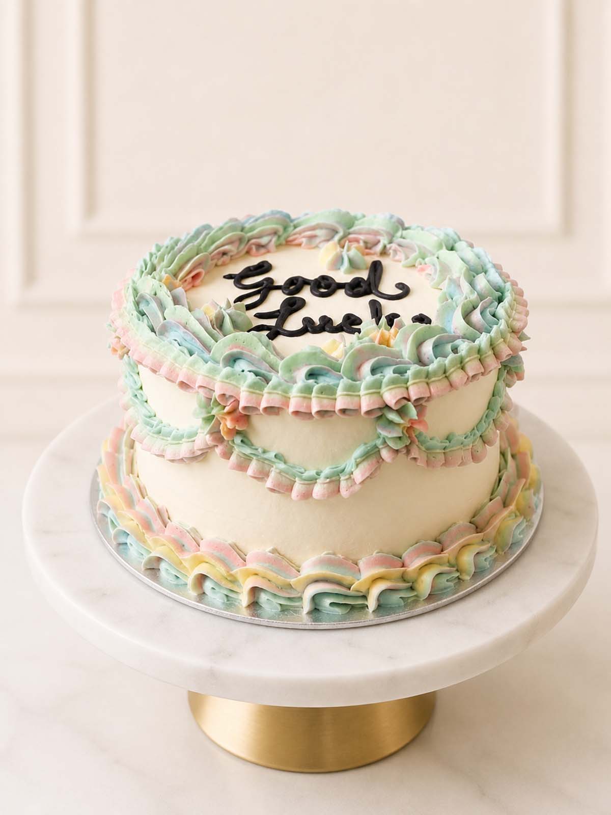 Customisable Good Luck celebration cake featuring retro Lambeth-style Swiss meringue buttercream piping and a hand-piped black buttercream message, perfect for new jobs, farewells, and new beginnings. Delivered in London.