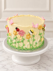 Three-quarter view of Secret Garden Cake with pastel flowers, butterflies and garden insects