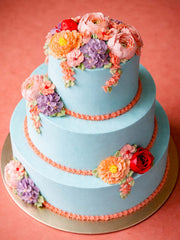Top-down view of the Floral Buttercream Wedding Cake showing a bouquet of hand-piped roses, peonies, and blossoms on blue vanilla Swiss meringue buttercream.