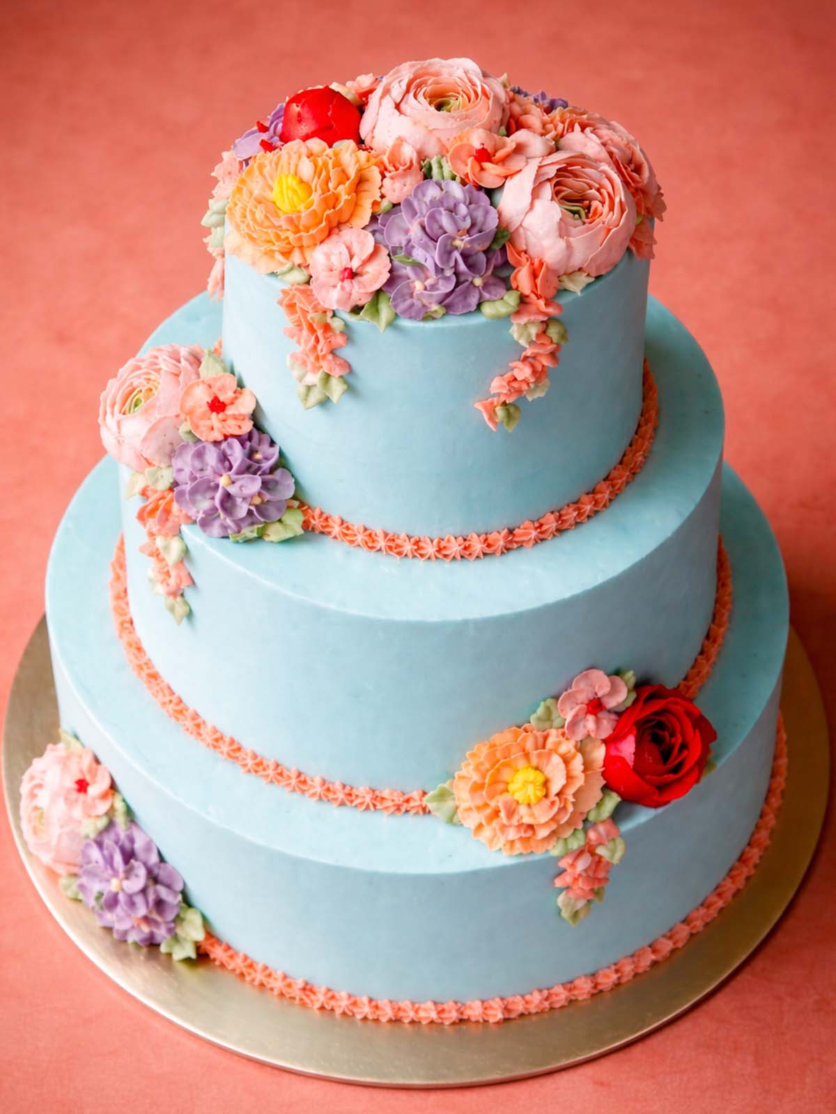 Top-down view of the Floral Buttercream Wedding Cake showing a bouquet of hand-piped roses, peonies, and blossoms on blue vanilla Swiss meringue buttercream.