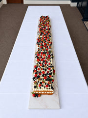 Overhead view of the two-metre Victoria Sponge Table Runner Cake topped with fresh berries