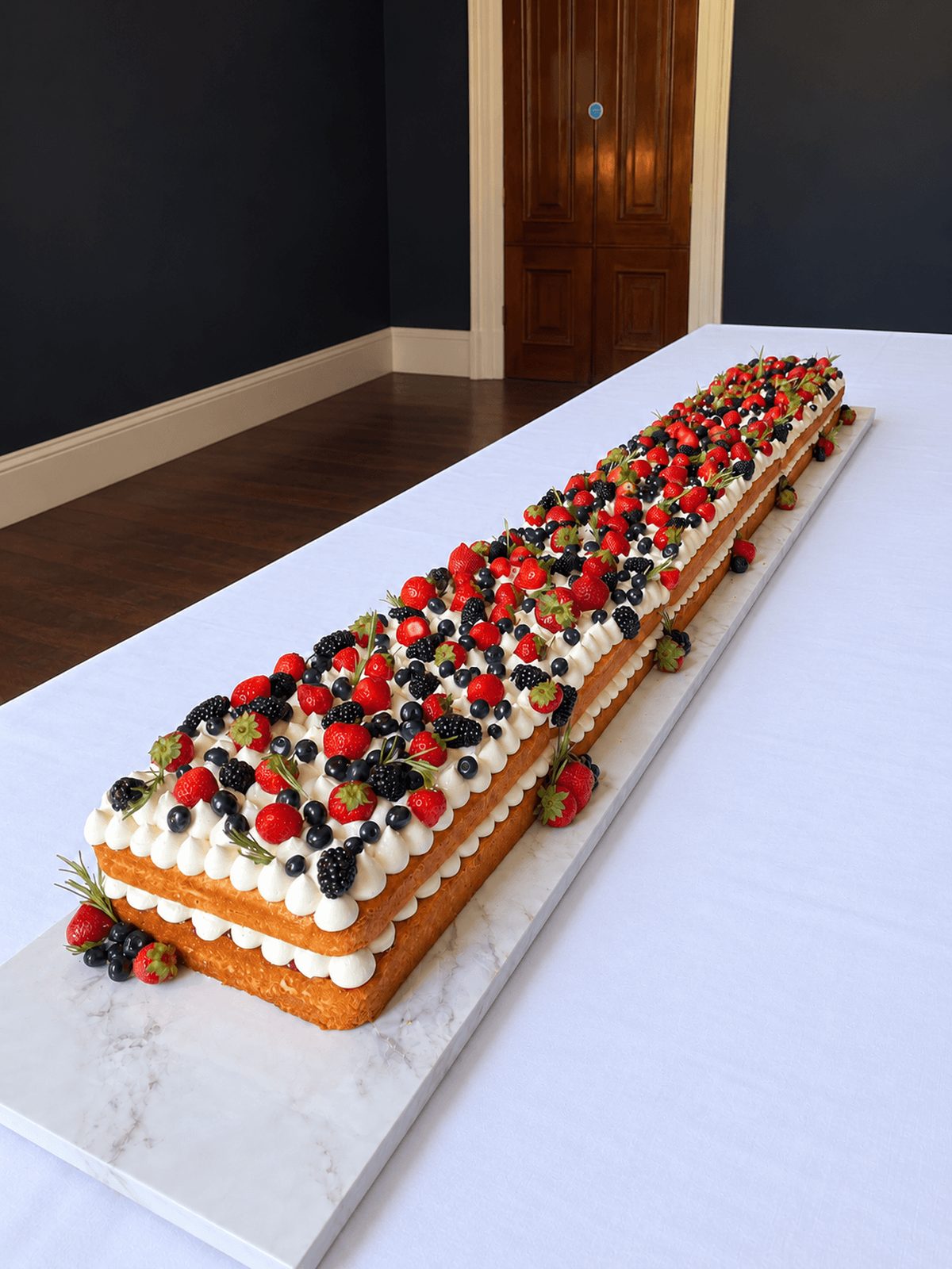 Three-quarter view of the two-metre Victoria Sponge Table Runner Cake with fresh berries
